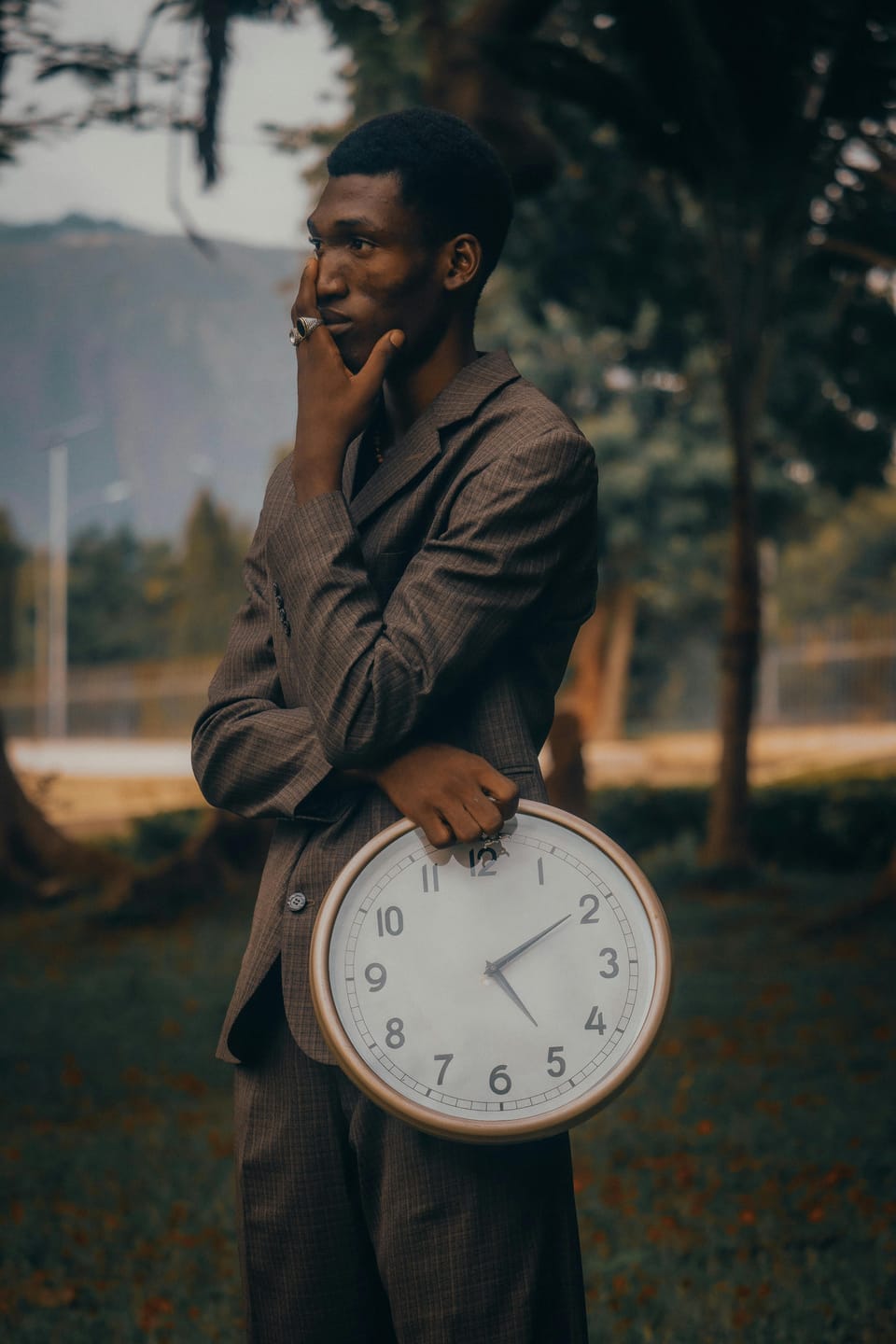 Contemplative man holding a clock outdoors