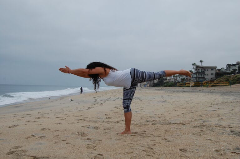 Warrior: Black woman in virabhadrasana 3 on a beach